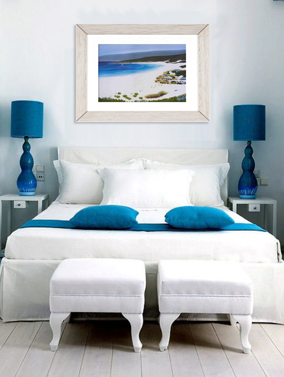 a framed limited edition print of Smiths Beach on the wall of an austeer blu and white bedroom